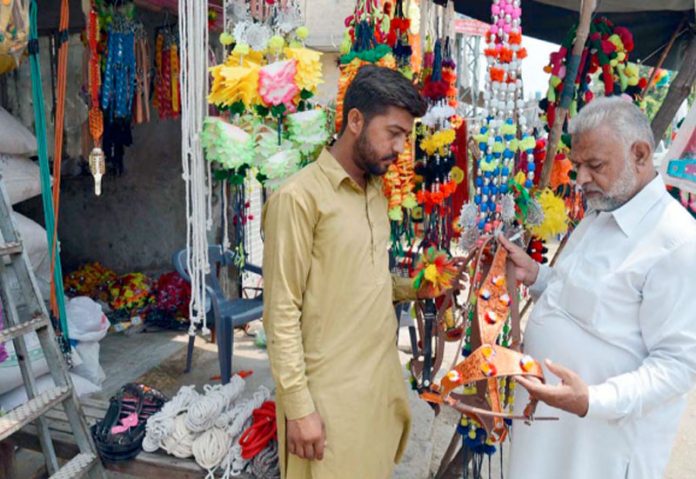 پشاور،شہری دکاندار سے جانوروں کو سجانے کے لیے سامان خرید رہا ہے