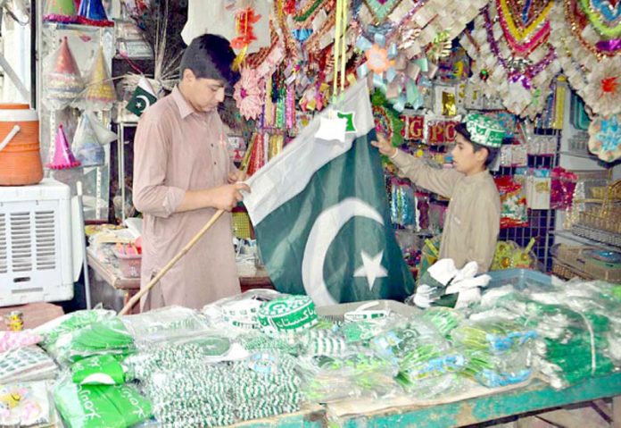 کوئٹہ ،جشن آزادی کے سلسلے میں دکاندار سبز پرچم گاہک کو دکھارہا ہے